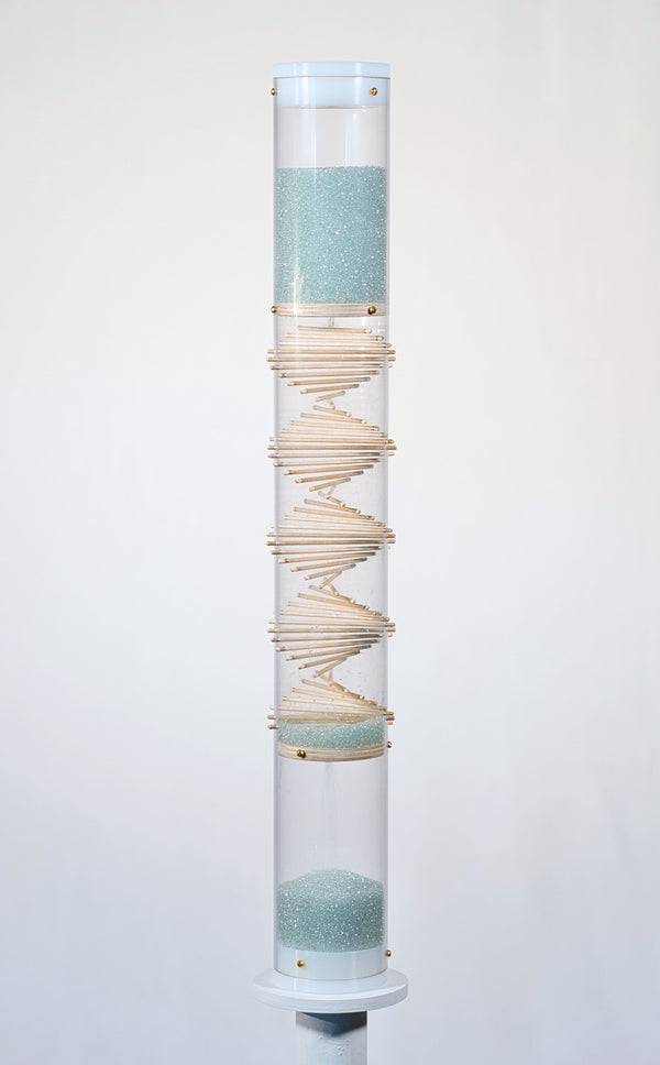 Pale blue beads shimmer in a clear tube with a visible wooden spiral. The beads are flowing from top to bottom and a sound is produced when they hit and bounce off of the visible spiral. The rainstick duration lasts for 3 minutes.