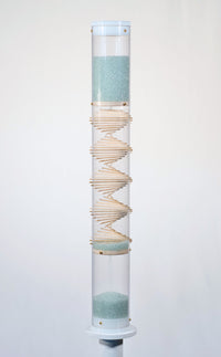 Pale blue beads shimmer in a clear tube with a visible wooden spiral. The beads are flowing from top to bottom and a sound is produced when they hit and bounce off of the visible spiral. The rainstick duration lasts for 3 minutes.