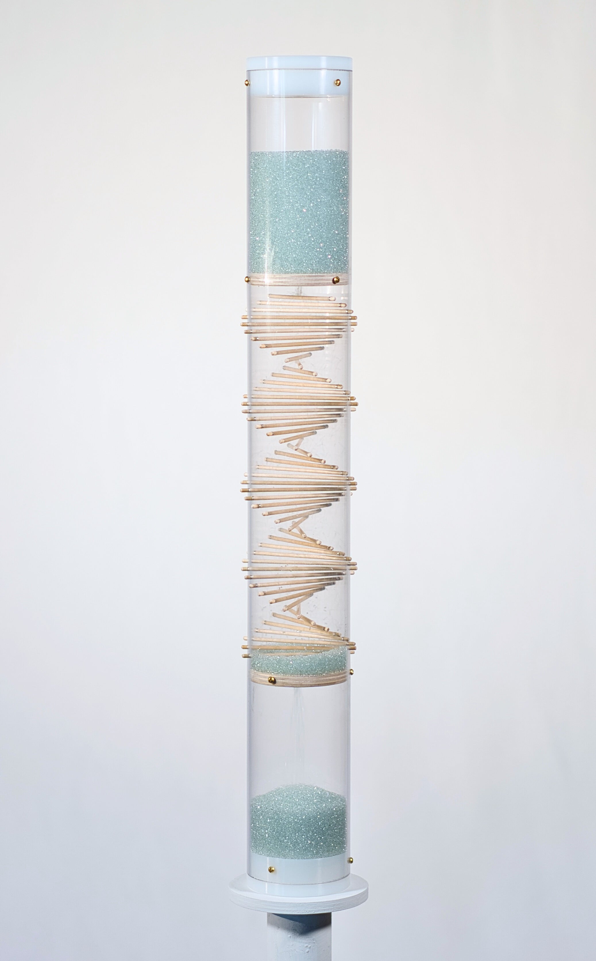 Pale blue beads shimmer in a clear tube with a visible wooden spiral. The beads are flowing from top to bottom and a sound is produced when they hit and bounce off of the visible spiral. The rainstick duration lasts for 3 minutes.