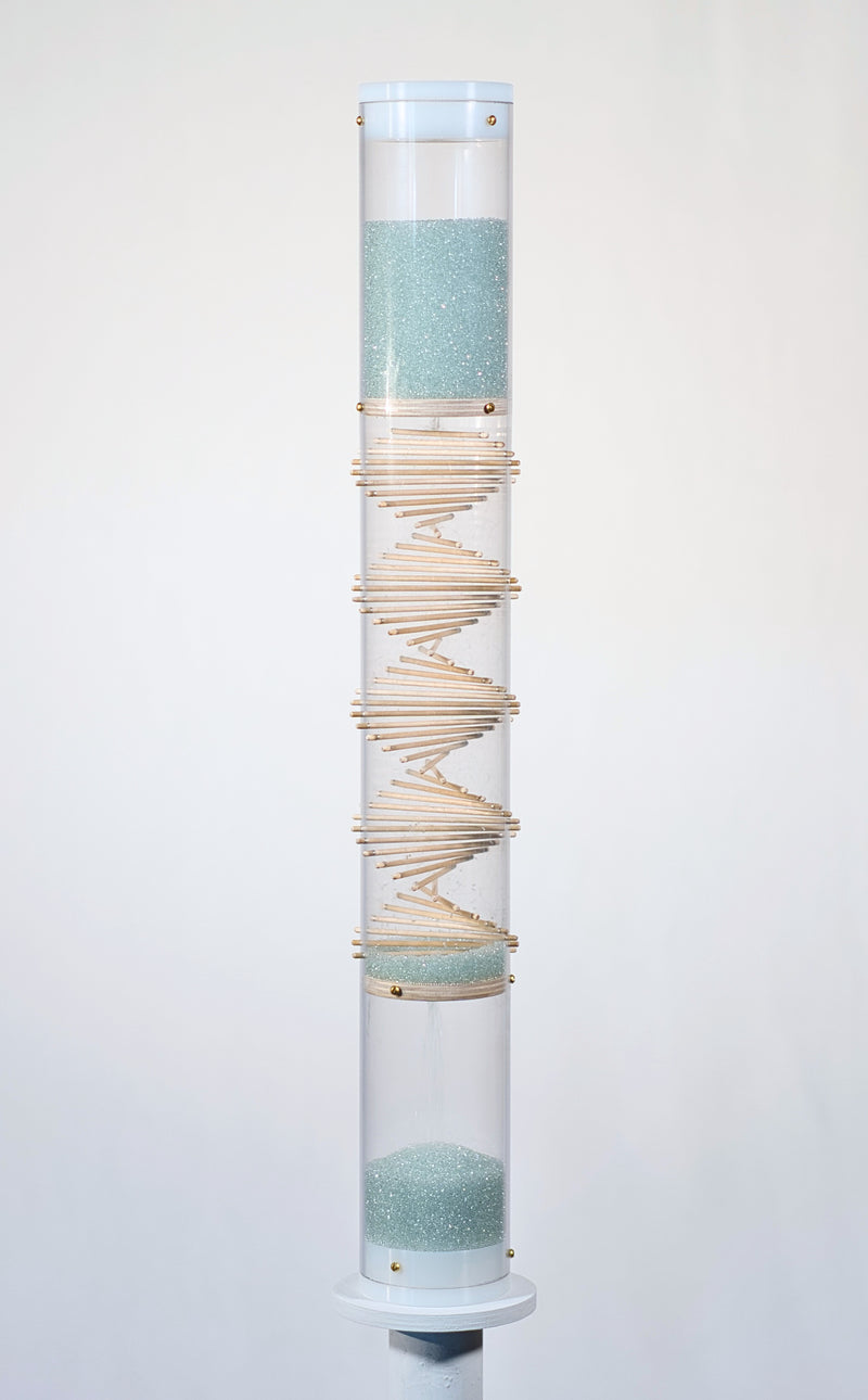 Pale blue beads shimmer in a clear tube with a visible wooden spiral. The beads are flowing from top to bottom and a sound is produced when they hit and bounce off of the visible spiral. The rainstick duration lasts for 3 minutes.