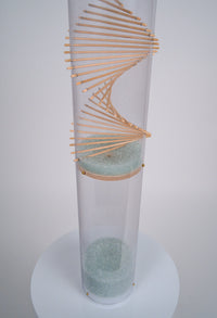 An aesthetically pleasing wood spiral design protrudes through a clear tube with pale blue glass microbeads descending down. It's a sound sculpture rainstick instrument that has a duration of 20 minutes, made by Rainstick Dreams in Pittsburgh, PA, USA.