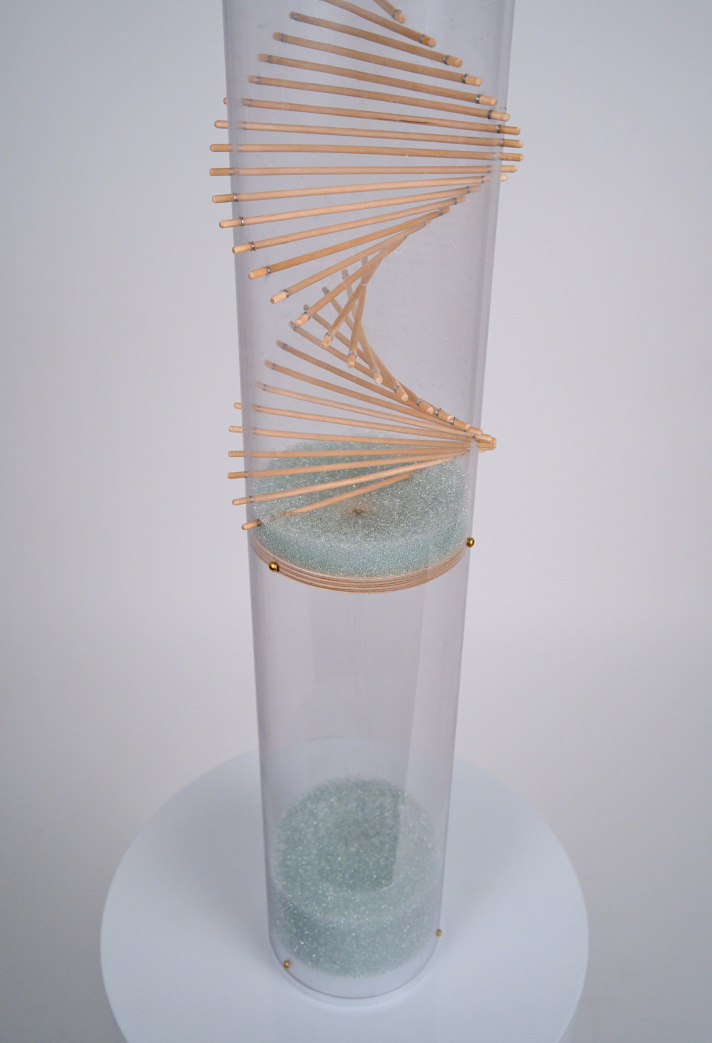 An aesthetically pleasing wood spiral design protrudes through a clear tube with pale blue glass microbeads descending down. It's a sound sculpture rainstick instrument that has a duration of 20 minutes, made by Rainstick Dreams in Pittsburgh, PA, USA.
