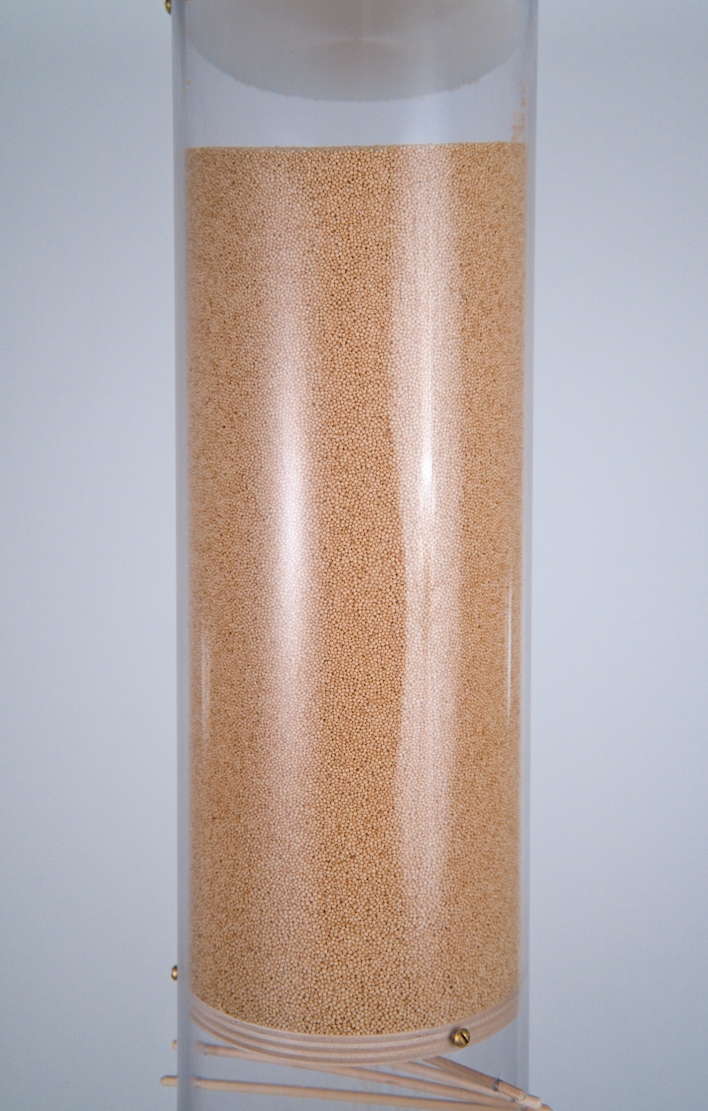 Millions of tiny tan amaranth seeds are in the upper reservoir of the extra large 20 minute rainstick by Rainstick Dreams. The upper part of the beautiful visible spiral appears at the bottom of the photo. The rainstick instrument has a clear tube so all the inner workings are visible.