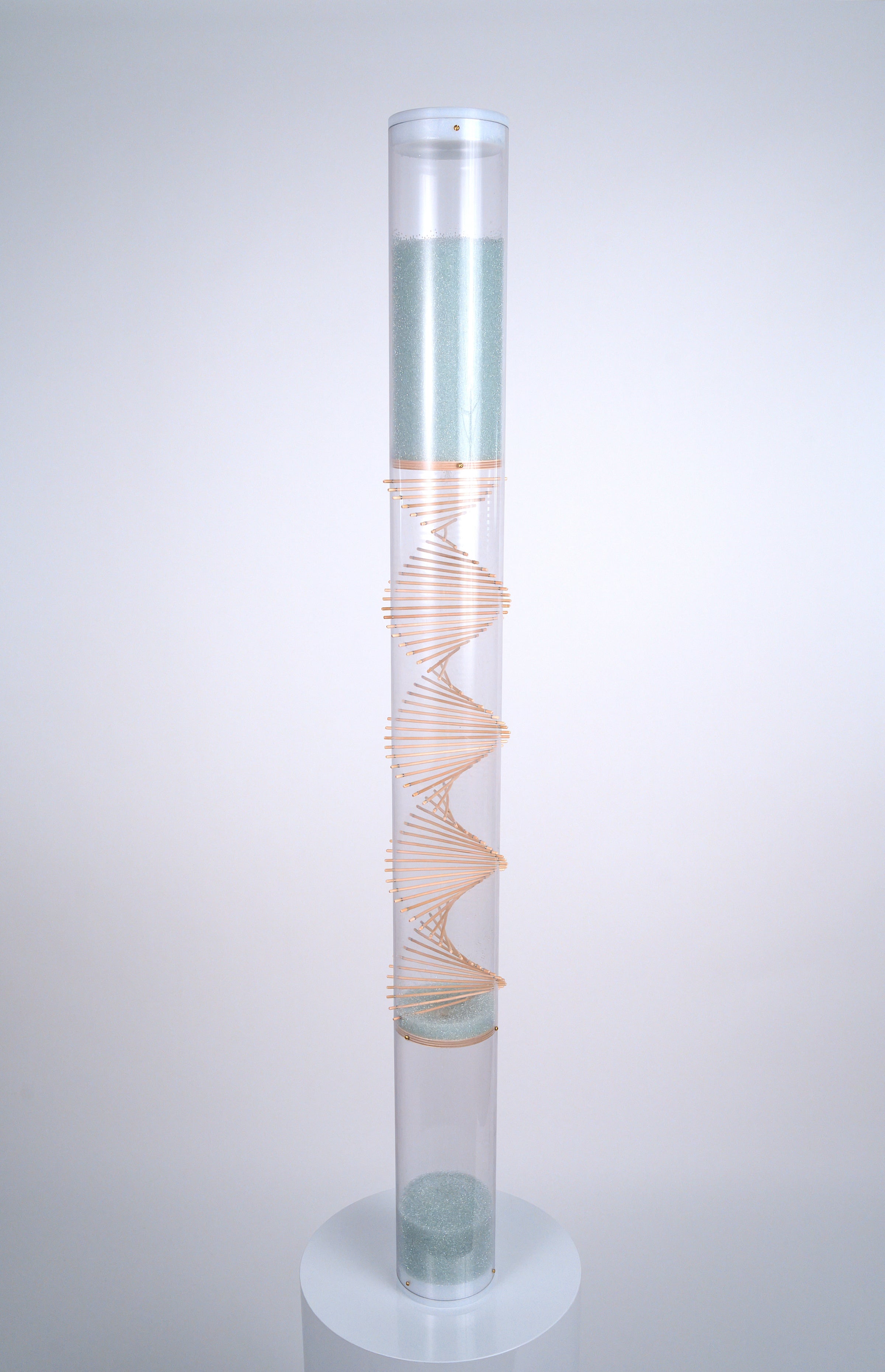 A 4' tall clear tube rainstick instrument featuring a raw wood spiral through the center stands on a white pedestal. Pale blue glass beads at the top flow down and bounce off the spiral of sticks, producing a medium rain sound. This is the XL Microbeads Spiral Sounds Rainstick by Rainstick Dreams. Its long duration rain sound lasts for 20 minutes, and is a perfect grounding tool for relaxation, as a sleep aid, for meditation, for sound baths and sound healing, for massage, during yoga practices.