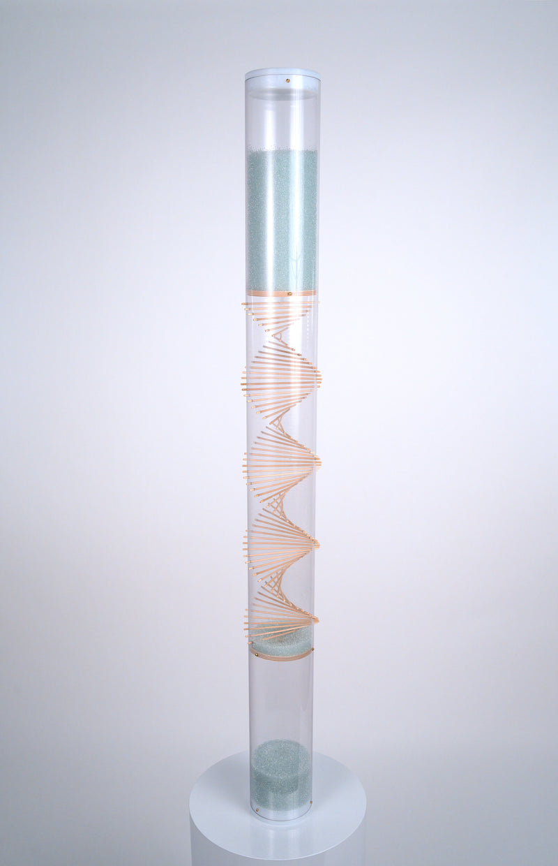 A 4' tall clear tube rainstick instrument featuring a raw wood spiral through the center stands on a white pedestal. Pale blue glass beads at the top flow down and bounce off the spiral of sticks, producing a medium rain sound. This is the XL Microbeads Spiral Sounds Rainstick by Rainstick Dreams. Its long duration rain sound lasts for 20 minutes, and is a perfect grounding tool for relaxation, as a sleep aid, for meditation, for sound baths and sound healing, for massage, during yoga practices.