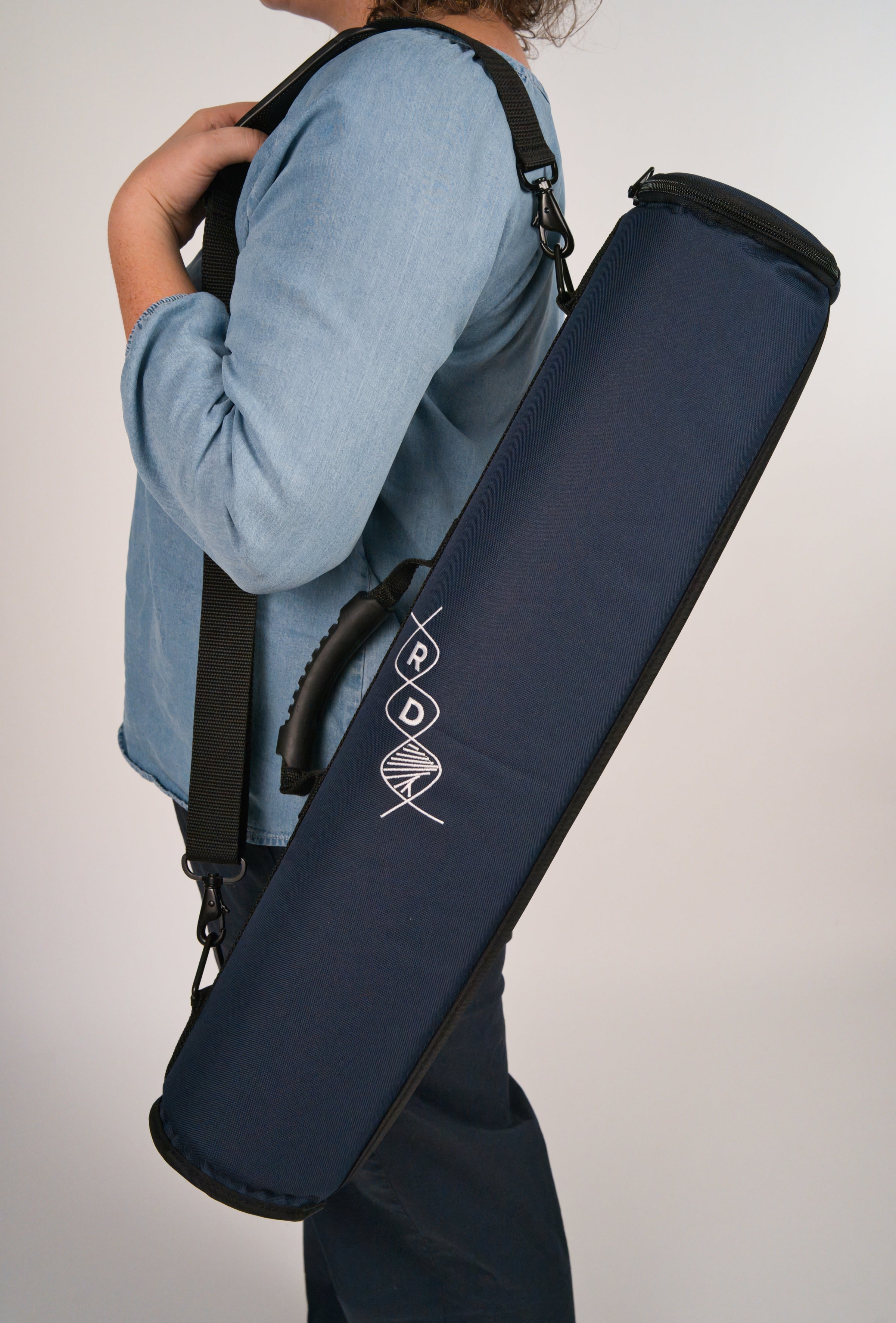 Person holding a navy blue instrument case featuring the RD helix logo over their shoulder in front of a plain background.