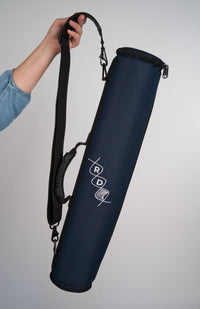 Navy blue rainstick instrument case with RD helix logo, durable handle and shoulder strap being held by a person's hand against a white backdrop.