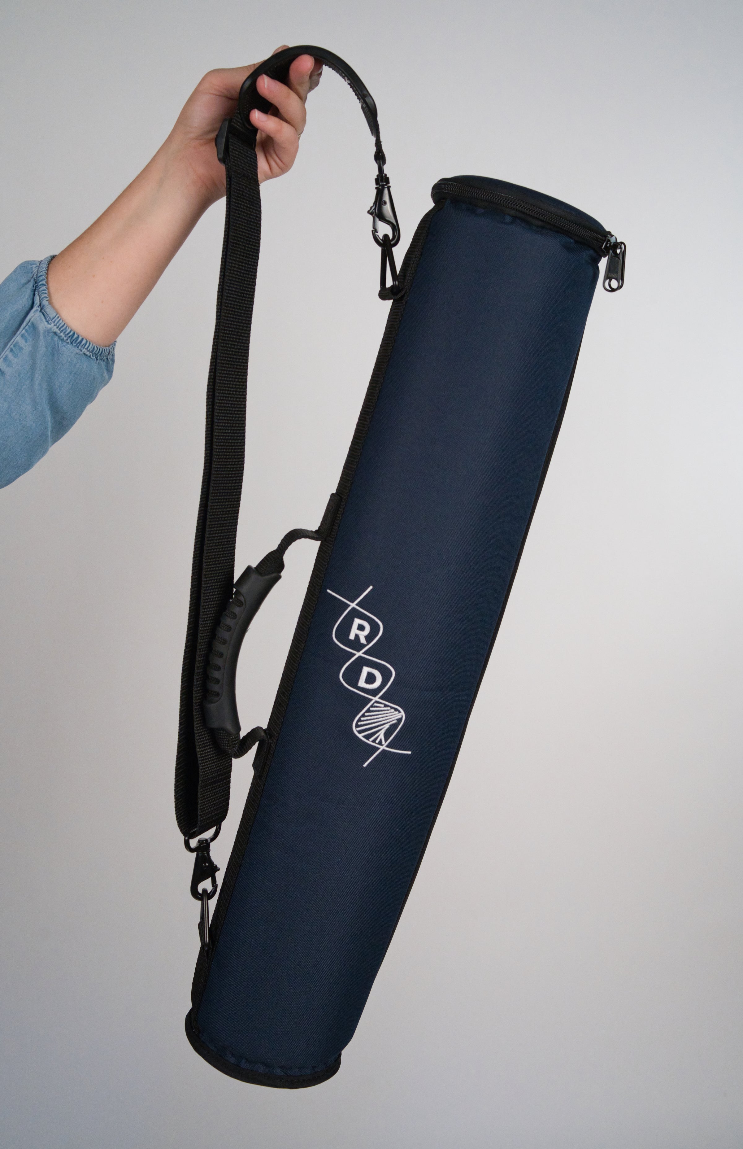 Navy blue rainstick instrument case with RD helix logo, durable handle and shoulder strap being held by a person's hand against a white backdrop.