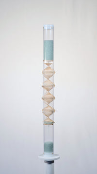 Pale blue beads shimmer in a clear tube with a visible wooden spiral. The beads are flowing from top to bottom and a sound is produced when they hit and bounce off of the visible spiral. This is a 90 second spiral rainstick made by Rainstick Dreams.