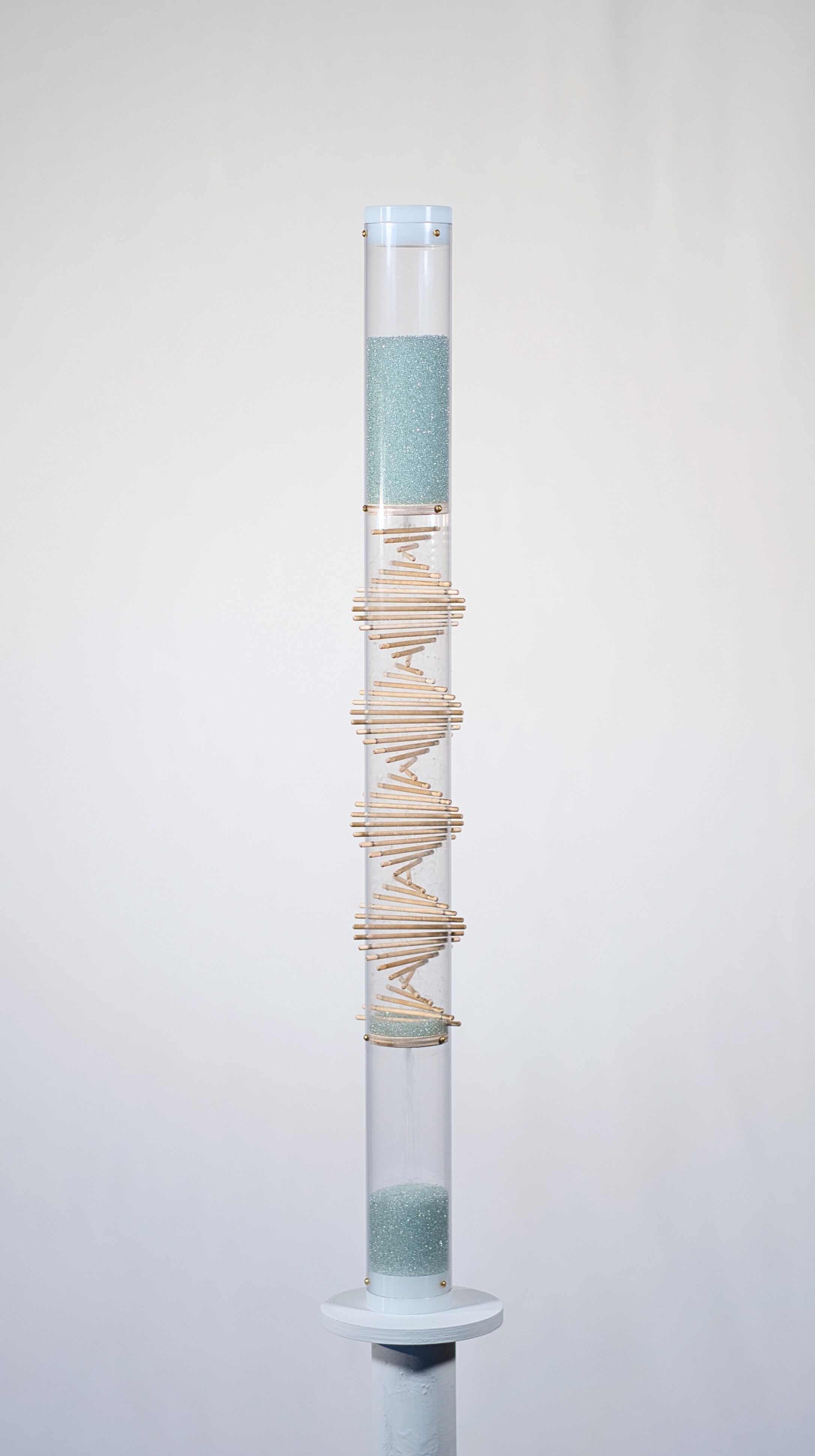 Pale blue beads shimmer in a clear tube with a visible wooden spiral. The beads are flowing from top to bottom and a sound is produced when they hit and bounce off of the visible spiral. This is a 90 second spiral rainstick made by Rainstick Dreams.